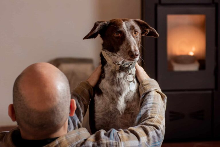 Uomo con cane davanti a stufa a pellet: calore accogliente dall'Austria